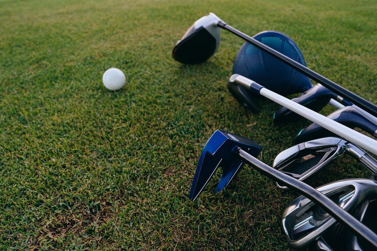 services-02 A close-up view of golf clubs and a golf ball on a lush green grass field.